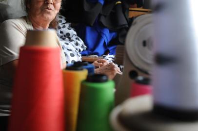  Costureira Ingerburg Ramers com peça de roupas, linhas e tesoura.