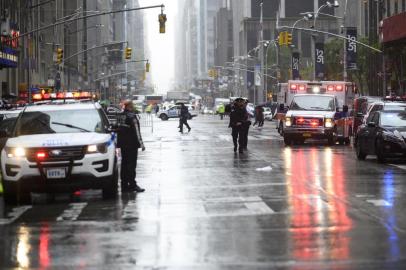 Policemen stand near emergency services vehicles after a helicopter crash-landed on top of a building in midtown Manhattan in New York on June 10, 2019. - Speaking at the scene New York Governor Andrew Cuomo told reporters there had been casualties on board the helicopter, but that no one in the building had been hurt. (Photo by Johannes EISELE / AFP)