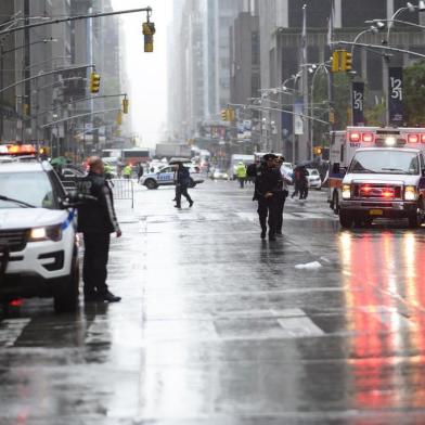 Policemen stand near emergency services vehicles after a helicopter crash-landed on top of a building in midtown Manhattan in New York on June 10, 2019. - Speaking at the scene New York Governor Andrew Cuomo told reporters there had been casualties on board the helicopter, but that no one in the building had been hurt. (Photo by Johannes EISELE / AFP)