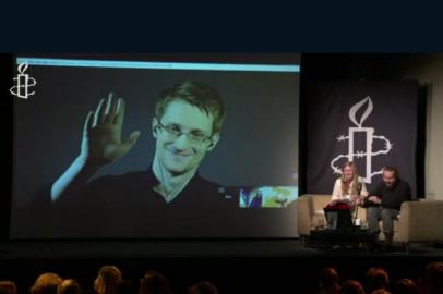 Falando por videoconferência em um ato realizado pela Anistia Internacional, em Londres, Edward Snowden qualificou de histórica a reforma que reduz os poderes da NSA. Reprodução Anistia Internacional/AFP