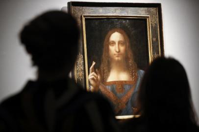 (FILES) In this file photo taken on October 24, 2017 Christies employees pose in front of a painting entitled Salvator Mundi by Italian polymath Leonardo da Vinci at a photocall at Christies auction house in central London ahead of its sale at Christies New York on November 15, 2017. - Later this year, the Louvre museum in Paris will host an exhibition grouping masterpieces of the great Italian painter Leonardo da Vinci to mark his death 500 years ago in France.The Salvator Mundi, sold at auction as a work by Leonardo for a record $450 million dollars in 2017, has not been displayed in public since, as doubts swirl about its ownership, whereabouts and authenticity. (Photo by Tolga Akmen / AFP) / RESTRICTED TO EDITORIAL USE - MANDATORY MENTION OF THE ARTIST UPON PUBLICATION - TO ILLUSTRATE THE EVENT AS SPECIFIED IN THE CAPTION