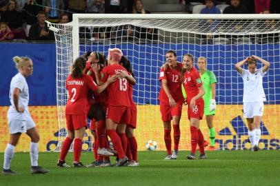 New Zealands defender Ria Percival (hidden) is congratulated by teammates after scoring a goal vies with Canadas forward Janine Beckie during the France 2019 Womens World Cup Group E football match between Canada and New Zealand, on June 15, 2019, at the Alpes Stadium in Grenoble, central-eastern France. (Photo by Jean-Pierre Clatot / AFP)