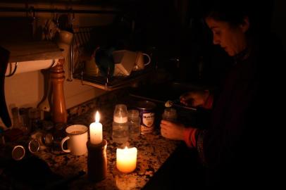 A woman prepares milk bottles using candles at her home in Montevideo on June 16, 2019 during a power cut. - A massive outage blacked out Argentina and Uruguay Sunday, leaving both South American countries without electricity, power companies said. (Photo by MIGUEL ROJO / AFP)