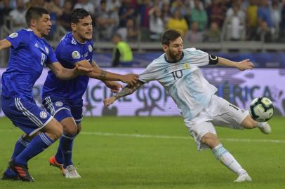 Argentina Lionel Messi (R) strikes the ball as he is marked by Paraguai Rodrigo Rojas (L) and Gustavo Gomez during the Copa America Copa América football tournament group match at the Mineirao Stadium in Belo Horizonte, Brazil, on June 19, 2019. (Photo by Luis ACOSTA / AFP)