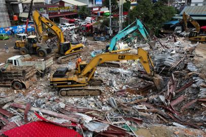 Rescue workers use earthmovers to clear debris as they search for victims a day after an under-construction building collapsed in Sihanoukville on June 23, 2019. At least 17 people are dead after a Chinese-constructed building collapsed in a Cambodian resort town, where rescue workers picked through a massive heap of rubble Sunday in a desperate search for survivors. SUN RETHY Kun / AFP