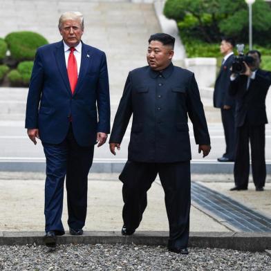 North Korea's leader Kim Jong Un and US President Donald Trump cross south of the Military Demarcation Line that divides North and South Korea, after Trump briefly stepped over to the northern side, in the Joint Security Area (JSA) of Panmunjom in the Demilitarized zone (DMZ) on June 30, 2019. (Photo by Brendan Smialowski / AFP)