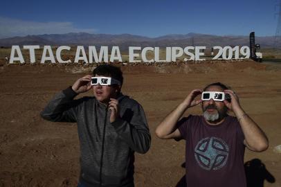  Tourists try special glasses to watch an eclipse at the entrance of an astronomical camp which expects to receive thousands of tourists to observe the July 2 total solar eclipse, in the commune of Vallenar in the Atacama desert about 600 km north of Santiago, on July 1, 2019. - A total solar eclipse will be visible from small parts of Chile and Argentina on July 2. (Photo by MARTIN BERNETTI / AFP)Editoria: SCILocal: VallenarIndexador: MARTIN BERNETTISecao: natural scienceFonte: AFPFotógrafo: STF