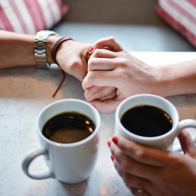 casal conversando tomando um café de mãos dadas