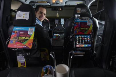 Motoristas de aplicativoSÃO PAULO, SP, 11.07.2019 - Retrato do motorista de aplicativo Pedro Madureira Neto, 39, que vende produtos dentro do seu veÃ­culo. No carro de Pedro Madureira Neto, 39, o chÃ¡ e o cafezinho sÃ£o cortesia que o motorista criado no interior faz questÃ£o de manter. Mas um cardÃ¡pio dÃ¡ outras opÃ§Ãµes: o passageiro da Uber, 99 ou Cabify pode escolher comprar chiclete, amendoim, chocolate, refrigerante, Ã¡gua de coco e atÃ© uma cerveja antes de chegar ao destino. Os preÃ§os variam de R$ 2 a R$ 9.  (Foto Danilo Verpa/Folhapress)