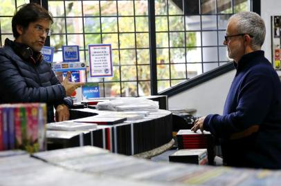 PORTO ALEGRE, RS, BRASIL, 01-07-2019: O proprietário Álvaro Bertani (D) atende o cliente Celso Rodrigues na locadora de DVDs E o vídeo levou, no bairro Jardim Botânico. (Foto: Mateus Bruxel / Agência RBS)