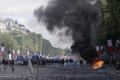 Members of the Gendarmerie stand in front of fences and a fire as protestors linked to the Yellow Vests (Gilets Jaunes) movement (unseen) take part in a demonstration on the side of the annual Bastille Day ceremony, on July 14, 2019, on the Champs-Elysees in Paris. (Photo by Kenzo TRIBOUILLARD / AFP)