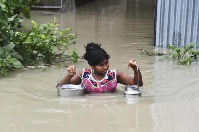 Data: 15/07/2019An Indian girl carries drinking water as she wades through flood waters at Pabhokathi village in Morigaon district of Indias Assam state on July 15, 2019. - Floods and landslides caused by the annual deluge have wreaked deadly havoc from the Himalayan foothills to low-lying camps housing Rohingya refugees, with officials warning tolls could rise as they scramble to reach affected communities. (Photo by Biju BORO / AFP)