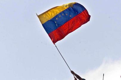 Soldados da Guarda Nacional venezuelana agitam a bandeira do país no topo do palácio presidencial de Miraflores, em Caracas.Venezuelan National Guard soldiers wave the national flag from the rooftop of the presidential palace Miraflores, 13 April 2002. Hundreds of supporters of ousted president Hugo Chavez marched on the presidential palace, demanding proof of the provisional governments claim that Chavez had resigned voluntarily.  AFP  PHOTO/Juan BARRETO#PÁGINA: 4 Fonte: AFP Fotógrafo: JUAN BARRETO