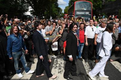 Beatles lookalike band Fab Gear and fans of The Beatles pose at the famous Abbey Road zebra crossing in London, England on August 8, 2019, the 50th anniversary of the day that the iconic Beatles album cover photograph was taken. (Photo by Daniel LEAL-OLIVAS / AFP)