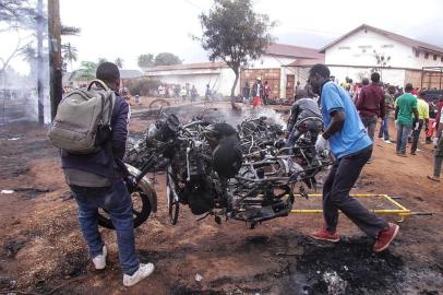 Two men carry the remains of a burnt out motorbike after a fuel tanker exploded on August 10, 2019, in Morogoro, 200 kilometres (120 miles) west of the Tanzanian capital Dar es Salaam. - At least 60 people perished in Tanzania when a fuel tanker overturned and then exploded as crowds of people rushed to syphon off leaking fuel. The deadly blast, which took place near the town of Morogoro, west of the economic capital Dar es Salaam, is the latest in a series of similar disasters in Africa. (Photo by STRINGER / AFP)