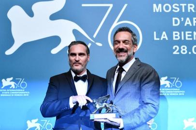 US director Todd Phillips (R), flanked by US actor Joaquin Phoenix, holds the Golden Lion award for Best Film he received for the movie Joker during the awards ceremony winners photocall of the 76th Venice Film Festival on September 7, 2019 at Venice Lido. (Photo by Alberto PIZZOLI / AFP)