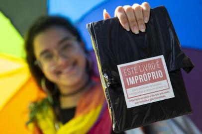 Handout picture released by the organisation of Rio Biennial Book Fair (Bienal do Livro do Rio) showing a woman holding one of 14,000 books of LGBT themes bought by Brazilian YouTuber Felipe Neto -who has more than 34 million subscribers to his channel- and distributed freely at the fair in protest to Rio de Janeiros Mayor Marcelo Crivella censorhip of a Marvels Comic Book -depicting two super-heroes kissing on its cover- in Rio de Janeiro, Brazil, on September 08, 2019. (Label reads This book is inappropriate for old-fashioned, retrograde and prejudiced people. Felipe Neto thanks your fight for love, inclusion and diversity) - Marvels Young Avengers: the Childrens Crusade quickly sold out on Friday after ultra-conservative Marcelo Crivella had ordered the book removed from sale because of its sexual content for minors. In a fresh legal twist -which suspends an interim injunction that had blocked the mayor from trying to ban the comic book on sale- a Brazilian court has allowed the evangelical mayor to confiscate books with LGBT content he considers inappropriate for minors, sparking fears over censorship and discrimination. (Photo by Fernando SOUZA / RIO DE JANEIRO BIENNIAL INTERNATIONAL BOOK FAIR / AFP) / RESTRICTED TO EDITORIAL USE - MANDATORY CREDIT AFP PHOTO / RIO DE JANEIRO BIENNIAL INTERNATIONAL BOOK FAIR - FERNANDO SOUZA  - NO MARKETING - NO ADVERTISING CAMPAIGNS - DISTRIBUTED AS A SERVICE TO CLIENTS