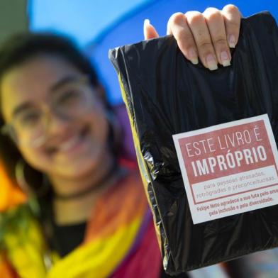 Handout picture released by the organisation of Rio Biennial Book Fair (Bienal do Livro do Rio) showing a woman holding one of 14,000 books of LGBT themes bought by Brazilian YouTuber Felipe Neto -who has more than 34 million subscribers to his channel- and distributed freely at the fair in protest to Rio de Janeiros Mayor Marcelo Crivella censorhip of a Marvels Comic Book -depicting two super-heroes kissing on its cover- in Rio de Janeiro, Brazil, on September 08, 2019. (Label reads This book is inappropriate for old-fashioned, retrograde and prejudiced people. Felipe Neto thanks your fight for love, inclusion and diversity) - Marvels Young Avengers: the Childrens Crusade quickly sold out on Friday after ultra-conservative Marcelo Crivella had ordered the book removed from sale because of its sexual content for minors. In a fresh legal twist -which suspends an interim injunction that had blocked the mayor from trying to ban the comic book on sale- a Brazilian court has allowed the evangelical mayor to confiscate books with LGBT content he considers inappropriate for minors, sparking fears over censorship and discrimination. (Photo by Fernando SOUZA / RIO DE JANEIRO BIENNIAL INTERNATIONAL BOOK FAIR / AFP) / RESTRICTED TO EDITORIAL USE - MANDATORY CREDIT AFP PHOTO / RIO DE JANEIRO BIENNIAL INTERNATIONAL BOOK FAIR - FERNANDO SOUZA  - NO MARKETING - NO ADVERTISING CAMPAIGNS - DISTRIBUTED AS A SERVICE TO CLIENTS