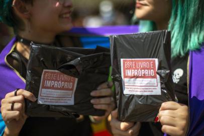 Handout picture released by the organisation of Rio Biennial Book Fair (Bienal do Livro do Rio) showing two women holding two of 14,000 books of LGBT themes bought by Brazilian YouTuber Felipe Neto -who has more than 34 million subscribers to his channel- and distributed freely at the fair in protest to Rio de Janeiros Mayor Marcelo Crivella censorhip of a Marvels Comic Book -depicting two super-heroes kissing on its cover- in Rio de Janeiro, Brazil, on September 08, 2019. (Label reads This book is inappropriate for old-fashioned, retrograde and prejudiced people. Felipe Neto thanks your fight for love, inclusion and diversity) - Marvels Young Avengers: the Childrens Crusade quickly sold out on Friday after ultra-conservative Marcelo Crivella had ordered the book removed from sale because of its sexual content for minors. In a fresh legal twist -which suspends an interim injunction that had blocked the mayor from trying to ban the comic book on sale- a Brazilian court has allowed the evangelical mayor to confiscate books with LGBT content he considers inappropriate for minors, sparking fears over censorship and discrimination. (Photo by Fernando SOUZA / RIO DE JANEIRO BIENNIAL INTERNATIONAL BOOK FAIR / AFP) / RESTRICTED TO EDITORIAL USE - MANDATORY CREDIT AFP PHOTO / RIO DE JANEIRO BIENNIAL INTERNATIONAL BOOK FAIR - FERNANDO SOUZA  - NO MARKETING - NO ADVERTISING CAMPAIGNS - DISTRIBUTED AS A SERVICE TO CLIENTS