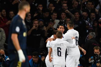 Paris Saint-Germains Argentine midfielder Angel Di Maria celebrates with teammates after scoring a goal as Real Madrids French forward Karim Benzema (L) looks at them during the UEFA Champions league Group A football match between Paris Saint-Germain and Real Madrid, at the Parc des Princes stadium, in Paris, on September 18, 2019. (Photo by MARTIN BUREAU / AFP)