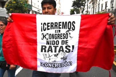 A demonstrator marches against corruption in Lima on September 30, 2019 after President Martin Vizcarra constitutionally dissolved the Congress, dominated by the opposition, after it refused to suspend a controversial appointment of new members of the Constitutional Court. - Vizcarra had originally threatened to dissolve Congress and force new legislative elections in June, unless lawmakers backed his anti-graft proposals. The proposal to lift legislative immunity turned into the source of the latest conflict between Perus executive and legislative branches; Vizcarra proposed giving the Supreme Court power to decide whether to strip a legislator of the protection. Congress, which currently holds the power to lift judicial immunity, rejected the idea. (Photo by Cris BOURONCLE / AFP)