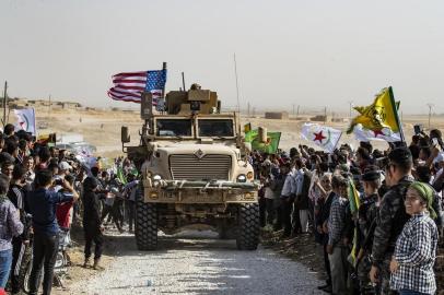 Syrian Kurds gather around a US armoured vehicle during a demonstration against Turkish threats next to a US-led international coalition base on the outskirts of Ras al-Ain town in Syrias Hasakeh province near the Turkish border on October 6, 2019. - Ankara had reiterated on October 5 an oft-repeated threat to launch an air and ground operation in Syria against a Kurdish militia it deems a terrorist group. (Photo by Delil SOULEIMAN / AFP)