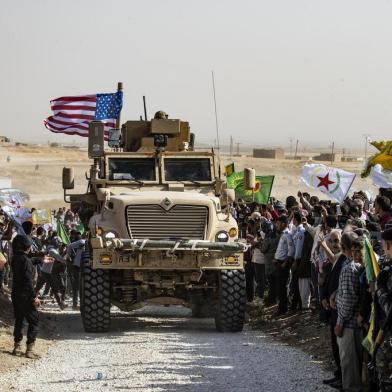 Syrian Kurds gather around a US armoured vehicle during a demonstration against Turkish threats next to a US-led international coalition base on the outskirts of Ras al-Ain town in Syrias Hasakeh province near the Turkish border on October 6, 2019. - Ankara had reiterated on October 5 an oft-repeated threat to launch an air and ground operation in Syria against a Kurdish militia it deems a terrorist group. (Photo by Delil SOULEIMAN / AFP)