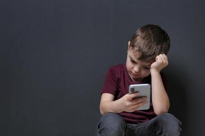  Sad little boy with mobile phone on black background, space for textFonte: 269566699