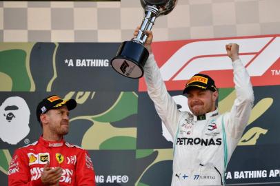 Mercedes Finnish driver Valtteri Bottas (R) raises the trophy to celebrate his victory beside second-placed Ferraris German driver Sebastian Vettel (L) on the podium after the Formula One Japanese Grand Prix in Suzuka on October 13, 2019. (Photo by TOSHIFUMI KITAMURA / AFP)