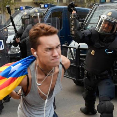 A Spanish national police officer uses his club to hit a protester during a demonstration called the Catalan pro-independence left youth group Arran on October 19, 2019 in Barcelona, a day after nearly 200 people were hurt in another night of violent clashes in Catalonia. - The deterioration came on the fifth consecutive day of protests in the Catalan capital and elsewhere over a Spanish courts jailing of nine separatist leaders on sedition charges over a failed independence bid two years ago (Photo by Josep LAGO / AFP)