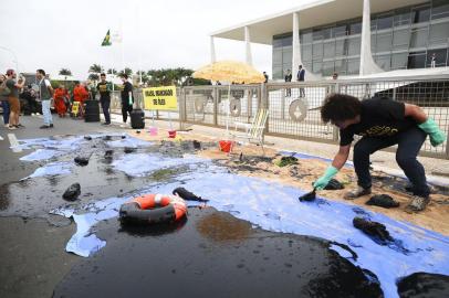 A Greenpeace activist spills fake oil during a protest in front of Planalto Palace in Brasilia, Brazil, Wednesday, October 23, 2019. - Greenpeace denounced what they call government negligence due to large blobs of oil staining more than 130 beaches in northeastern Brazil began appearing in early September and have now turned up along a 2,000km stretch of the Atlantic coastline. The source of the patches remain a mystery despite President Jair Bolsonaros assertions they came from outside the country and were possibly the work of criminals.