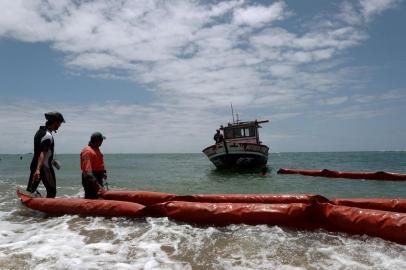 Municipal workers and firefighters are seen installing a floating barrier to contain oil spilled in Jaboatao dos Guararapes, Pernambuco state, Brazil, on October 21, 2019. - Large blobs of oil staining more than 130 beaches in northeastern Brazil began appearing in early September and have now turned up along a 2,000km stretch of the Atlantic coastline. The source of the patches remain a mystery despite President Jair Bolsonaros assertions they came from outside the country and were possibly the work of criminals. (Photo by / AFP)