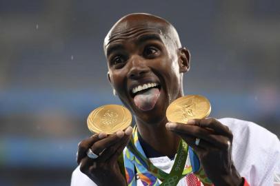 Gold medallist Britains Mo Farah celebrates near the podium for the Mens 5000m during the athletics event at the Rio 2016 Olympic Games at the Olympic Stadium in Rio de Janeiro on August 20, 2016. Eric FEFERBERG / AFP