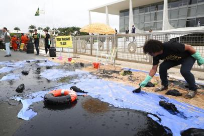  A Greenpeace activist spills fake oil during a protest in front of Planalto Palace in Brasilia, Brazil, Wednesday, October 23, 2019. - Greenpeace denounced what they call government negligence due to large blobs of oil staining more than 130 beaches in northeastern Brazil began appearing in early September and have now turned up along a 2,000km stretch of the Atlantic coastline. The source of the patches remain a mystery despite President Jair Bolsonaros assertions they came from outside the country and were possibly the work of criminals. (Photo by Sérgio Lima / AFP)Editoria: ENVLocal: BrasíliaIndexador: SERGIO LIMASecao: environmental pollutionFonte: AFPFotógrafo: STR