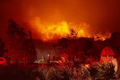 Firefighters survey Soda Rock Winery as it begins to burn during the Kincade fire in Healdsburg, California on October 27, 2019. - Powerful winds were fanning wildfires in northern California in potentially historic fire conditions, authorities said October 27, as tens of thousands of people were ordered to evacuate and sweeping power cuts began in the US state. (Photo by Josh Edelson / AFP)