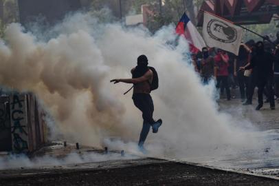 A demonstrator kicks a tear gas canister during clashes with security forces which erupted during a protest against the economic policies of the government of President Sebastian Pinera in Santiago, on November 4, 2019. - Unrest began in Chile last October 18 with protests against a rise in transport tickets and other austerity measures and descended into vandalism, looting, and clashes between demonstrators and police. Protesters are angry about low salaries and pensions, poor public healthcare and education, and a yawning gap between rich and poor. (Photo by Rodrigo ARANGUA / AFP)