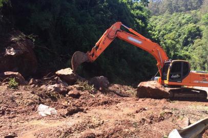 Escavadeira recolhendo pedras de barreira que caiu na ERS-122 em Farroupilha.