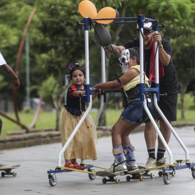  PORTO ALEGRE, RS, BRASIL - 09/11/2019Projeto possibilita que crianças com deficiência andem de skate. Na foto, Mariani de Borba Frank Athaíde dá carona para Laura Mendes da Silva, ambas empurradas pelo Daniel Paniagua