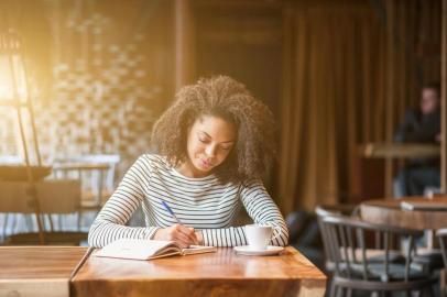 Pretty african woman is learning subject in cafeteriaPORTO ALEGRE, RS, BRASIL,09/04/2016-Mulher escrevendo. (Foto: Yakobchuk Olena / stock.adobe.com)Indexador: YacobchukFonte: 109588095