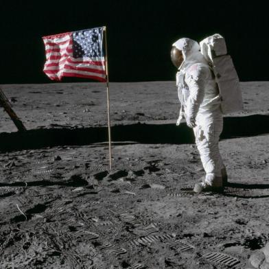 AS11-40-5875 (20 July 1969) --- Astronaut Edwin E. Aldrin Jr., lunar module pilot of the first lunar landing mission, poses for a photograph beside the deployed United States flag during an Apollo 11 extravehicular activity (EVA) on the lunar surface. The Lunar Module (LM) is on the left, and the footprints of the astronauts are clearly visible in the soil of the moon. Astronaut Neil A. Armstrong, commander, took this picture with a 70mm Hasselblad lunar surface camera. While astronauts Armstrong and Aldrin descended in the LM, the Eagle, to explore the Sea of Tranquility region of the moon, astronaut Michael Collins, command module pilot, remained with the Command and Service Modules (CSM) Columbia in lunar orbit. Photo credit: NASAO astronauta Edwin E. Aldrin Jr., piloto do módulo lunar da primeira missão de pouso lunar, posa para uma fotografia ao lado da bandeira dos Estados Unidos durante uma atividade extraveicular da Apollo 11 (EVA) na superfície lunar.APOLLO 11 ONBOARD PHOTO: GOOD VIEW OF ASTRONAUT FOOTPRINT IN LUNAR SOIL.