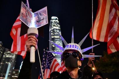 A participant holds a torch and wears headgear modelled after the Statue of Liberty as people assemble for a gathering of thanks at Edinburgh Place in Hong Kongs Central district on November 28, 2019, after US President Donald Trump signed legislation requiring an annual review of freedoms in Hong Kong. - China on November 28 threatened to retaliate after US President Donald Trump signed legislation supporting Hong Kong pro-democracy protesters, just as the worlds top two economies edge towards a trade truce. (Photo by Anthony WALLACE / AFP)