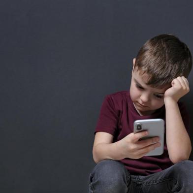  Sad little boy with mobile phone on black background, space for textFonte: 269566699