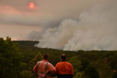 Residents watch a large bushfire as seen from Bargo, 150km southwest of Sydney, on December 19, 2019. - A state of emergency was declared in Australias most populated region on December 19 as an unprecedented heatwave fanned out-of-control bushfires, destroying homes and smothering huge areas with a toxic smoke. (Photo by Peter PARKS / AFP)<!-- NICAID(14363904) -->