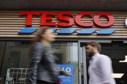 (FILES) In this file photo taken on September 30, 2019 people walk past at a Tesco Express in central London. - Supermarket giant Tesco has stopped production at a factory in China after one of its Christmas cards was found to contain a cry for help from a prisoner who made it, the store said on Sunday, December 22. (Photo by Tolga AKMEN / AFP)<!-- NICAID(14367639) -->