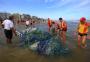 Redes de pesca de barco naufragado são retiradas da beira-mar em Capão da Canoa