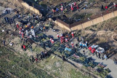 People and rescue teams are pictured amid bodies and debris after a Ukrainian plane carrying 176 passengers crashed near Imam Khomeini airport in the Iranian capital Tehran early in the morning on January 8, 2020, killing everyone on board. - The Boeing 737 had left Tehran's international airport bound for Kiev, semi-official news agency ISNA said, adding that 10 ambulances were sent to the crash site. (Photo by Rouhollah VAHDATI / ISNA / AFP)