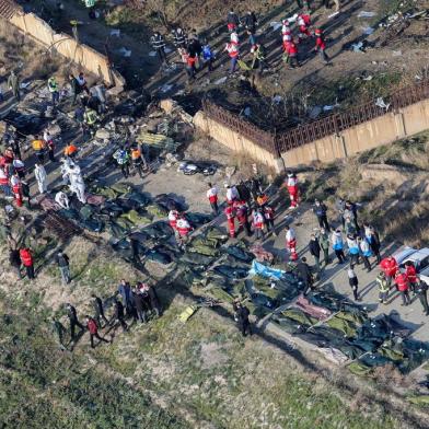 People and rescue teams are pictured amid bodies and debris after a Ukrainian plane carrying 176 passengers crashed near Imam Khomeini airport in the Iranian capital Tehran early in the morning on January 8, 2020, killing everyone on board. - The Boeing 737 had left Tehran's international airport bound for Kiev, semi-official news agency ISNA said, adding that 10 ambulances were sent to the crash site. (Photo by Rouhollah VAHDATI / ISNA / AFP)