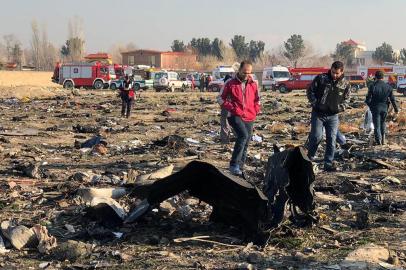 People walk near the wreckage after a Ukrainian plane carrying 176 passengers crashed near Imam Khomeini airport in Tehran early in the morning on January 8, 2020, killing everyone on board. - The Boeing 737 had left Tehran's international airport bound for Kiev, semi-official news agency ISNA said, adding that 10 ambulances were sent to the crash site. (Photo by - / AFP)