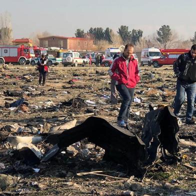 People walk near the wreckage after a Ukrainian plane carrying 176 passengers crashed near Imam Khomeini airport in Tehran early in the morning on January 8, 2020, killing everyone on board. - The Boeing 737 had left Tehran's international airport bound for Kiev, semi-official news agency ISNA said, adding that 10 ambulances were sent to the crash site. (Photo by - / AFP)