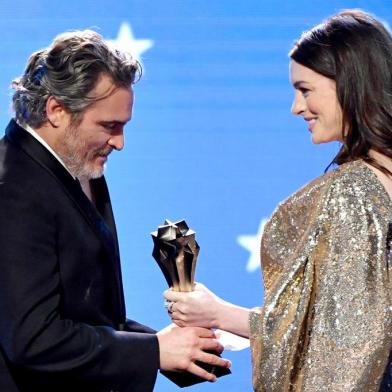 SANTA MONICA, CALIFORNIA - JANUARY 12: (L-R) Joaquin Phoenix accepts the Best Actor award for Joker from Anne Hathaway onstage during the 25th Annual Critics Choice Awards at Barker Hangar on January 12, 2020 in Santa Monica, California.   Amy Sussman/Getty Images/AFP<!-- NICAID(14385025) -->